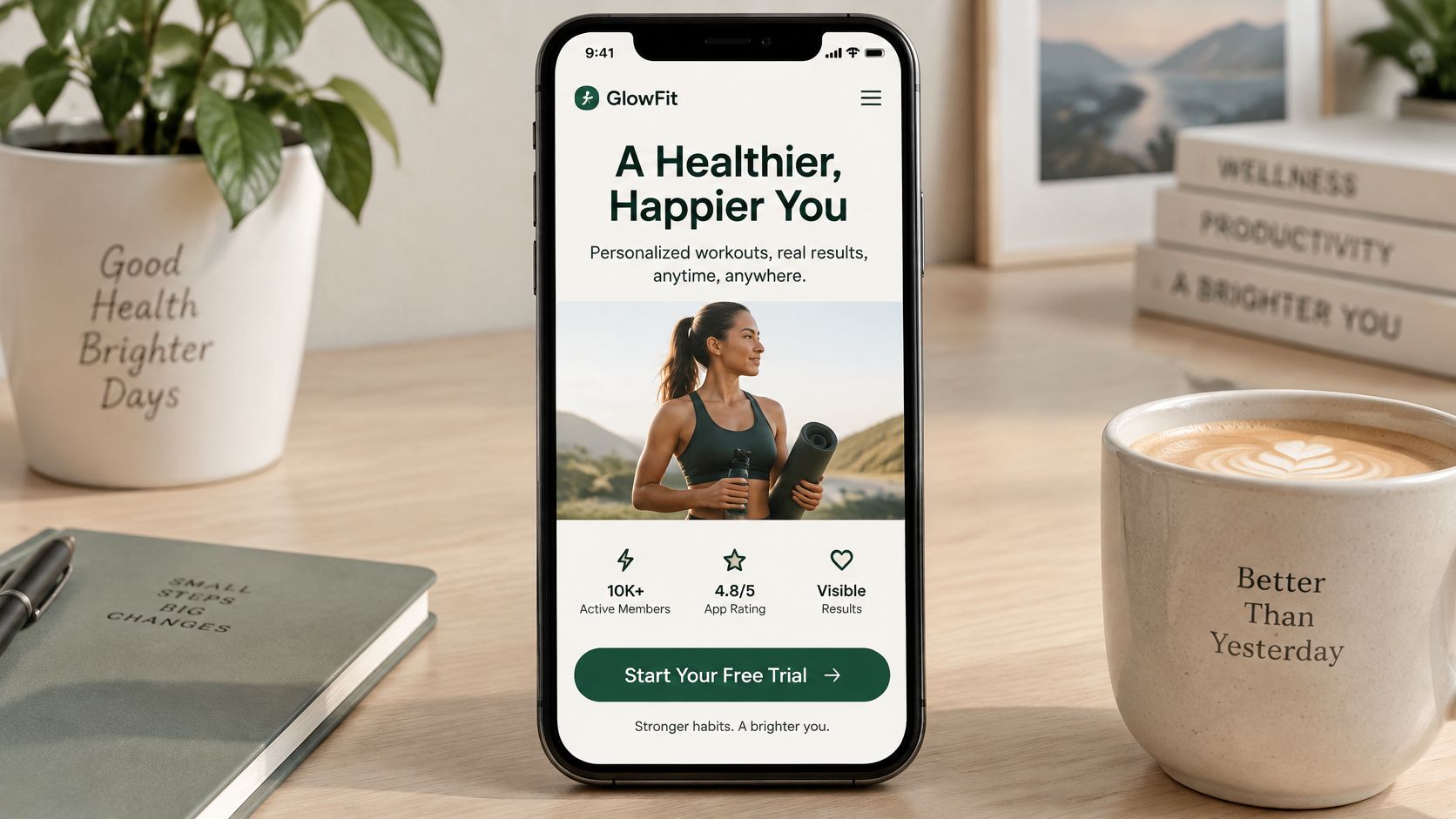 Un smartphone mostrando una aplicación de fitness llamada GlowFit sobre una mesa de madera con café y plantas.